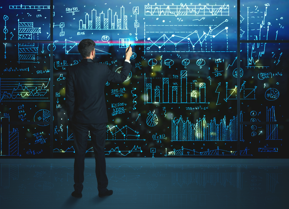 Businessman drawing business statistics on glass wall